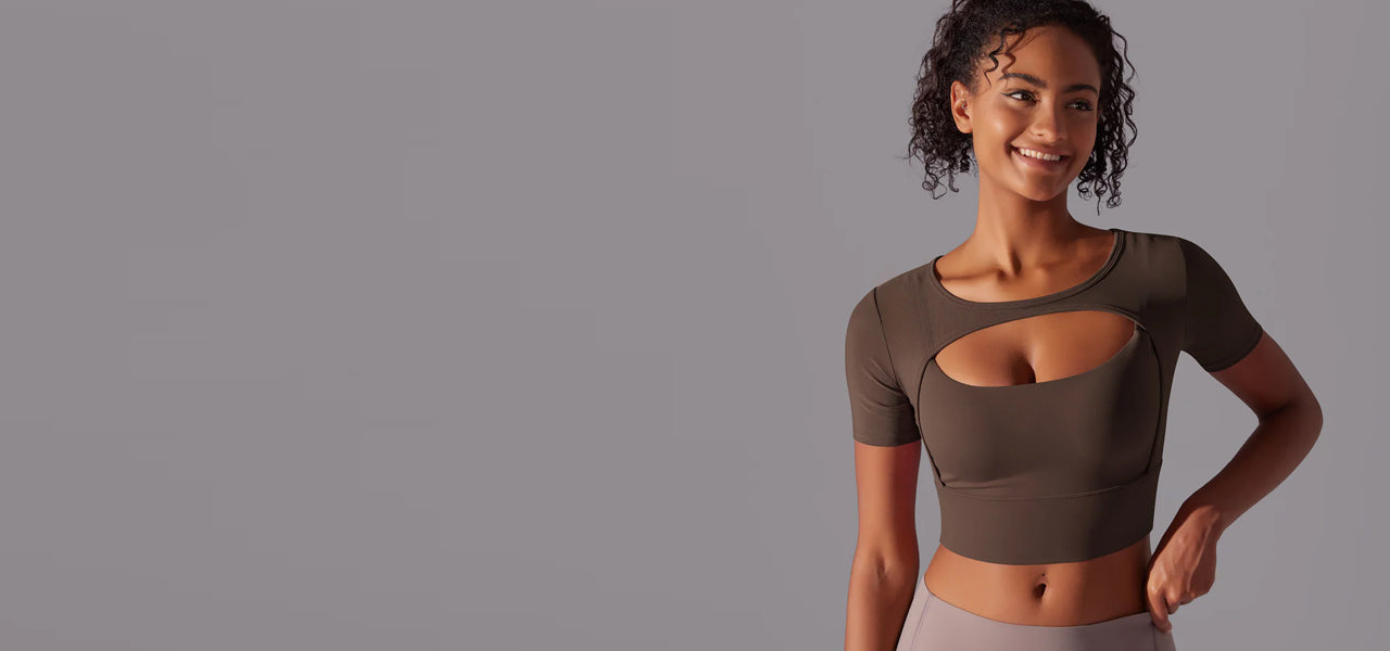 Woman wearing a brown crop top with cut-out design on a gray background